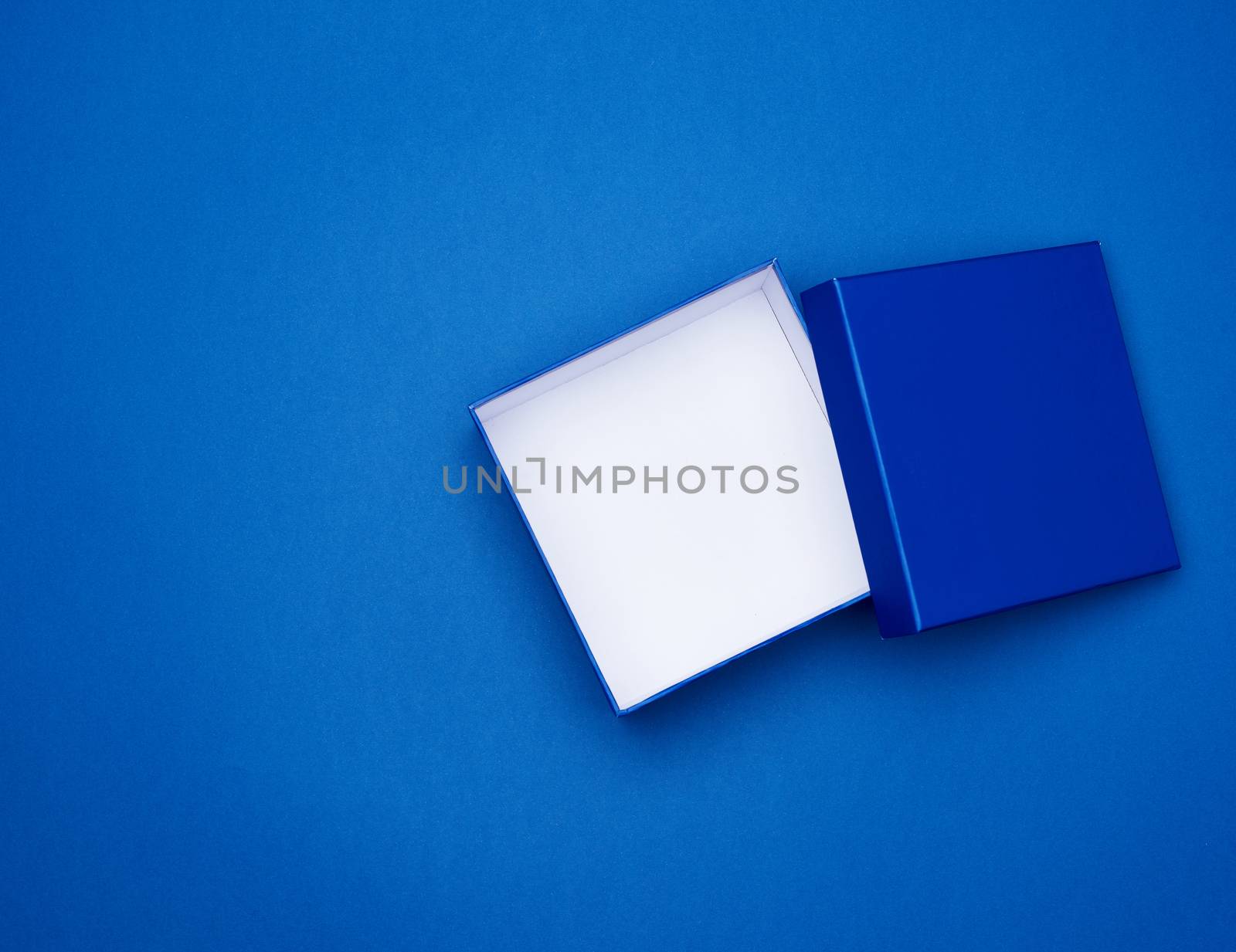 open blue square cardboard empty box, item lies on a blue classic background color, top view