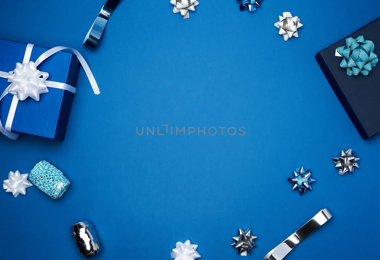 cardboard gift square boxes, bows, ribbons for packaging on a dark blue background, empty space in the middle, trend colors