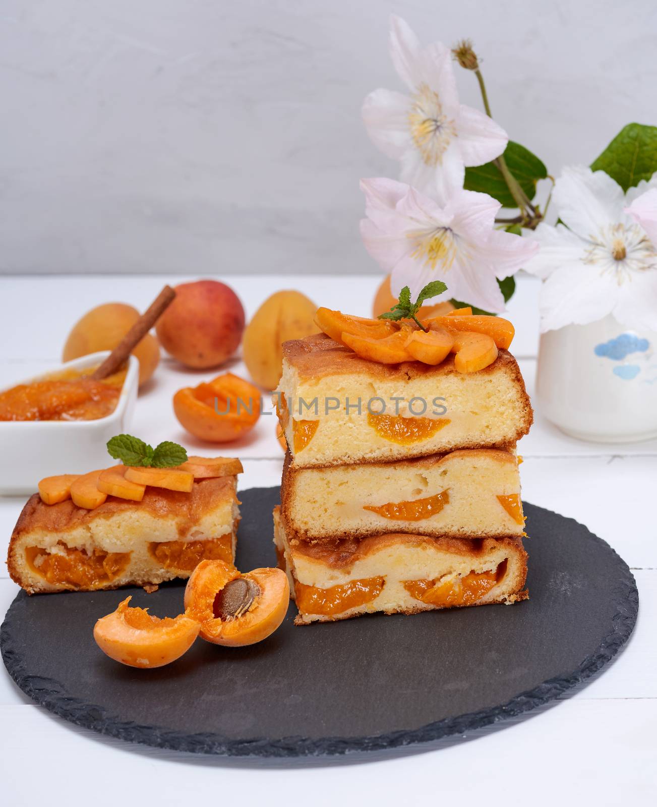 square pieces of apricot pie on a black graphite plate, sponge cake, close up