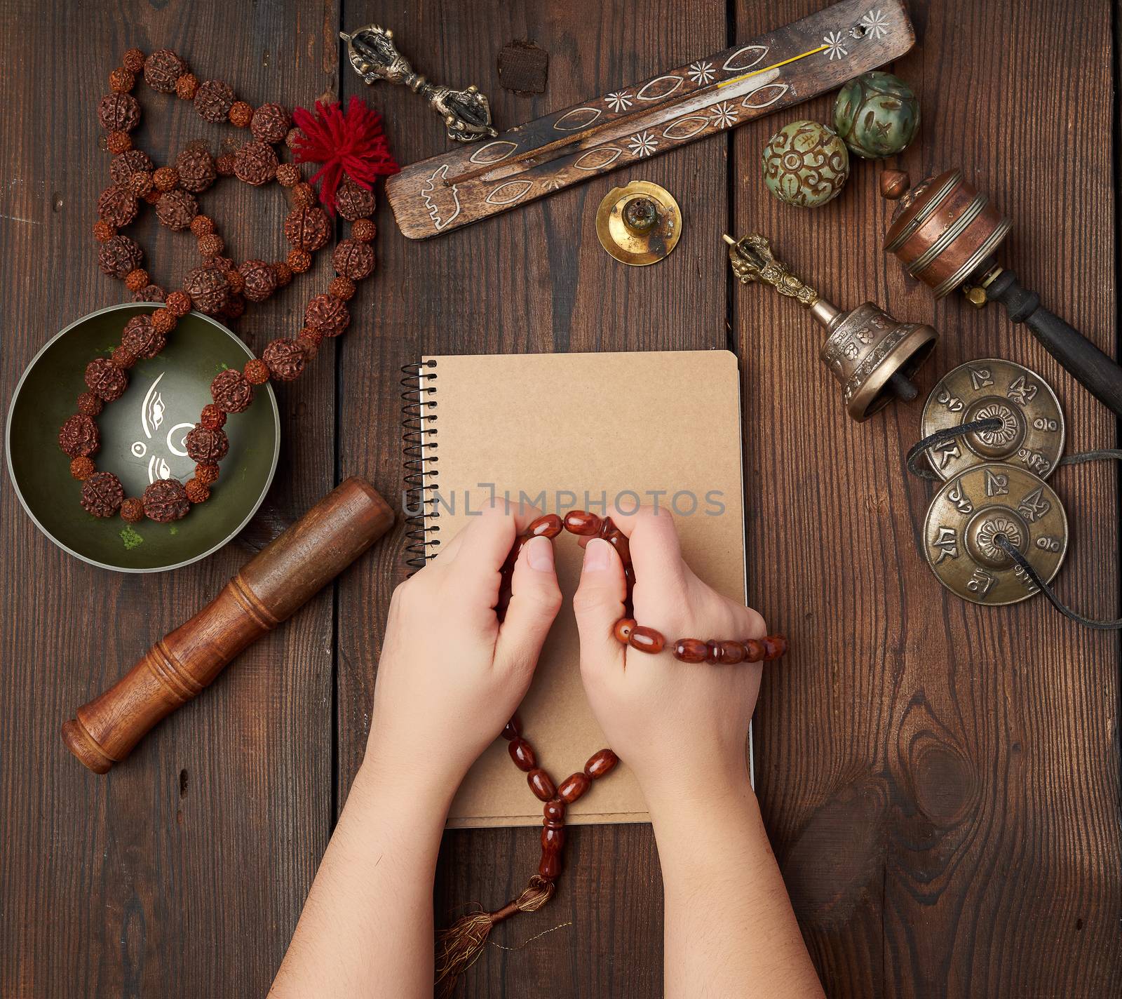 two hands in a prayer pose on a wooden brown table in the middle by ndanko