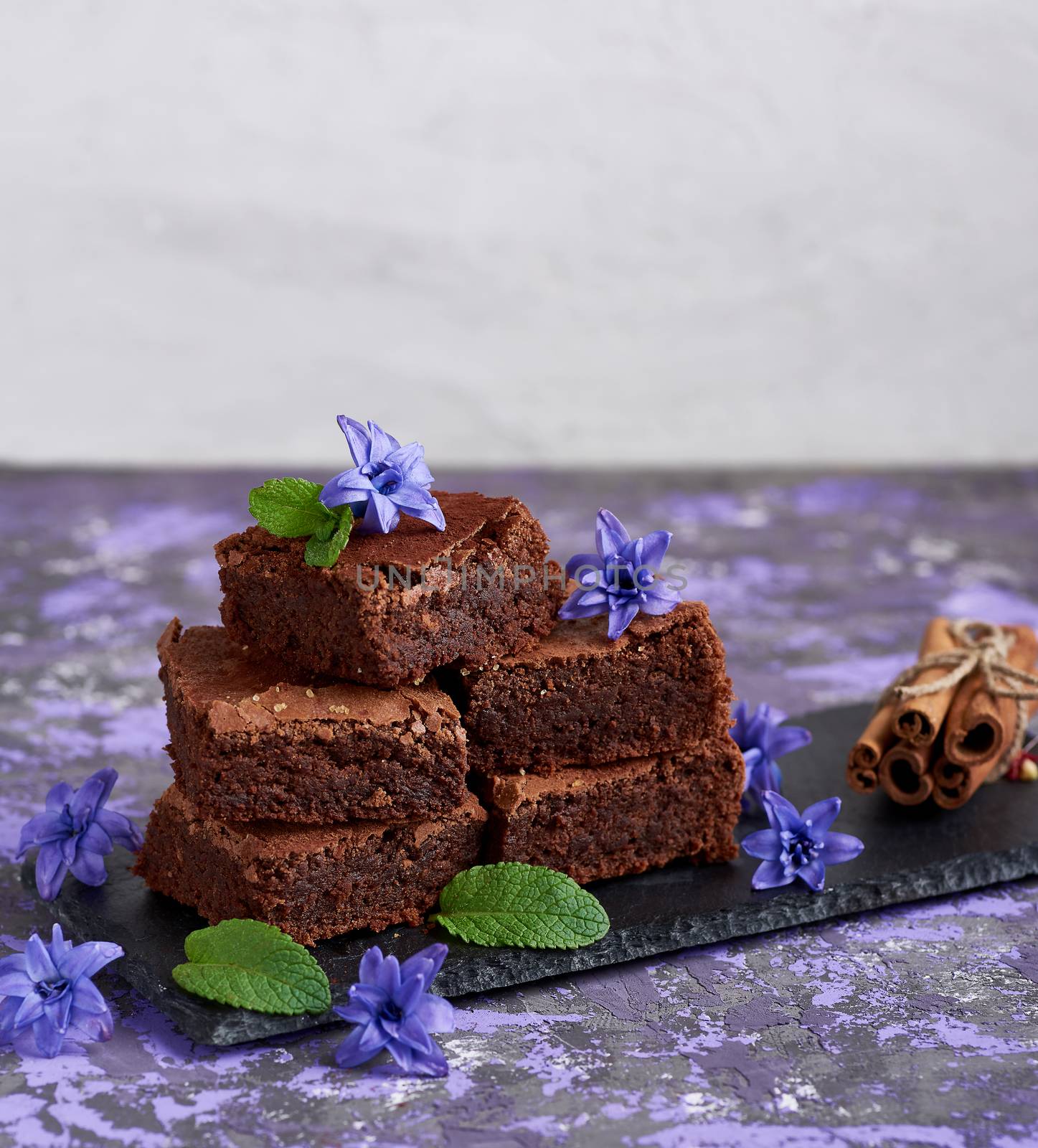 stack of square pieces of brownie on a black graphite plate by ndanko