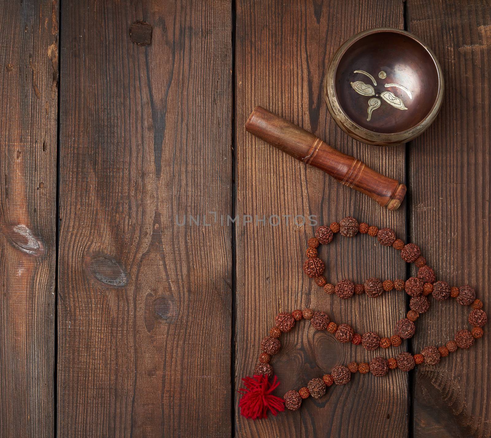 singing Tibetan copper bowl and wooden stick on a table of brown boards, top view, copy space