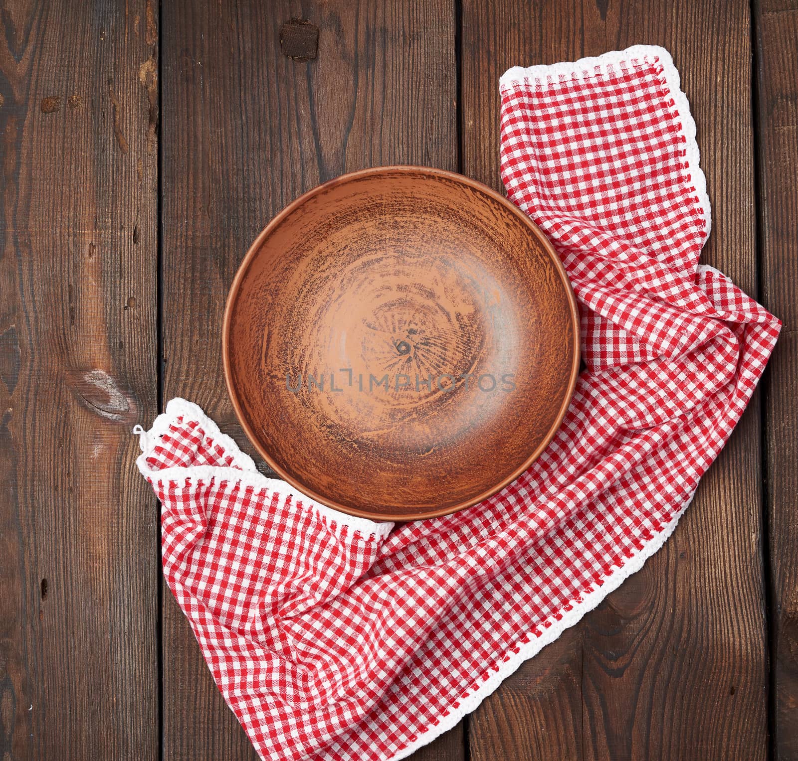 empty brown ceramic plates and red napkin on a wooden table, top view