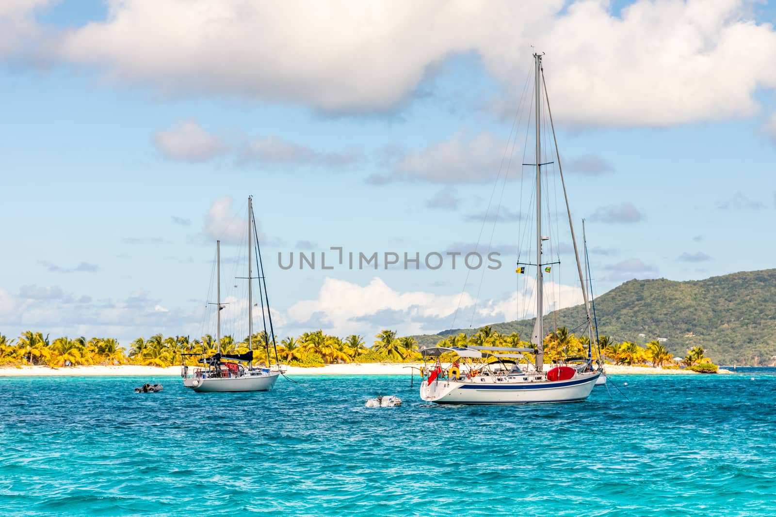 Turquoise sea and anchored yachts at Sandy beach island, near Ca by ambeon