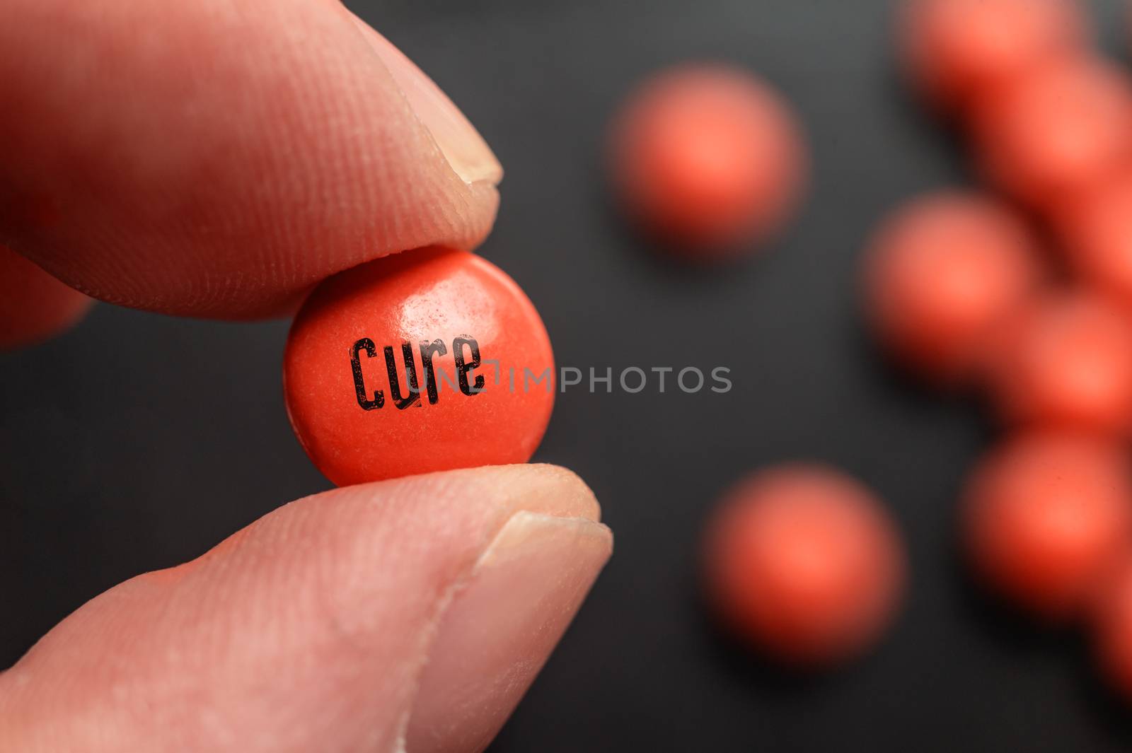 Fingers holding a pill with Cure label.