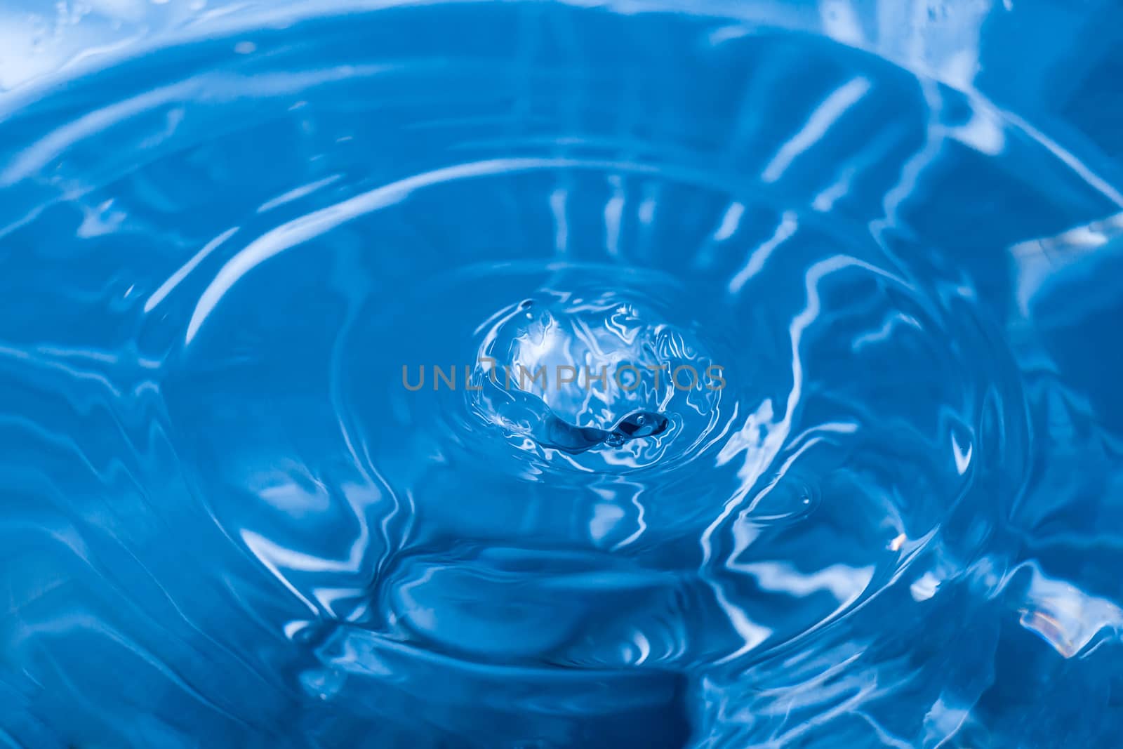 Water ripple background. Splashes from a drop of water. Raindrops on a blue background. The texture of the water. Aqua, turquoise, macro