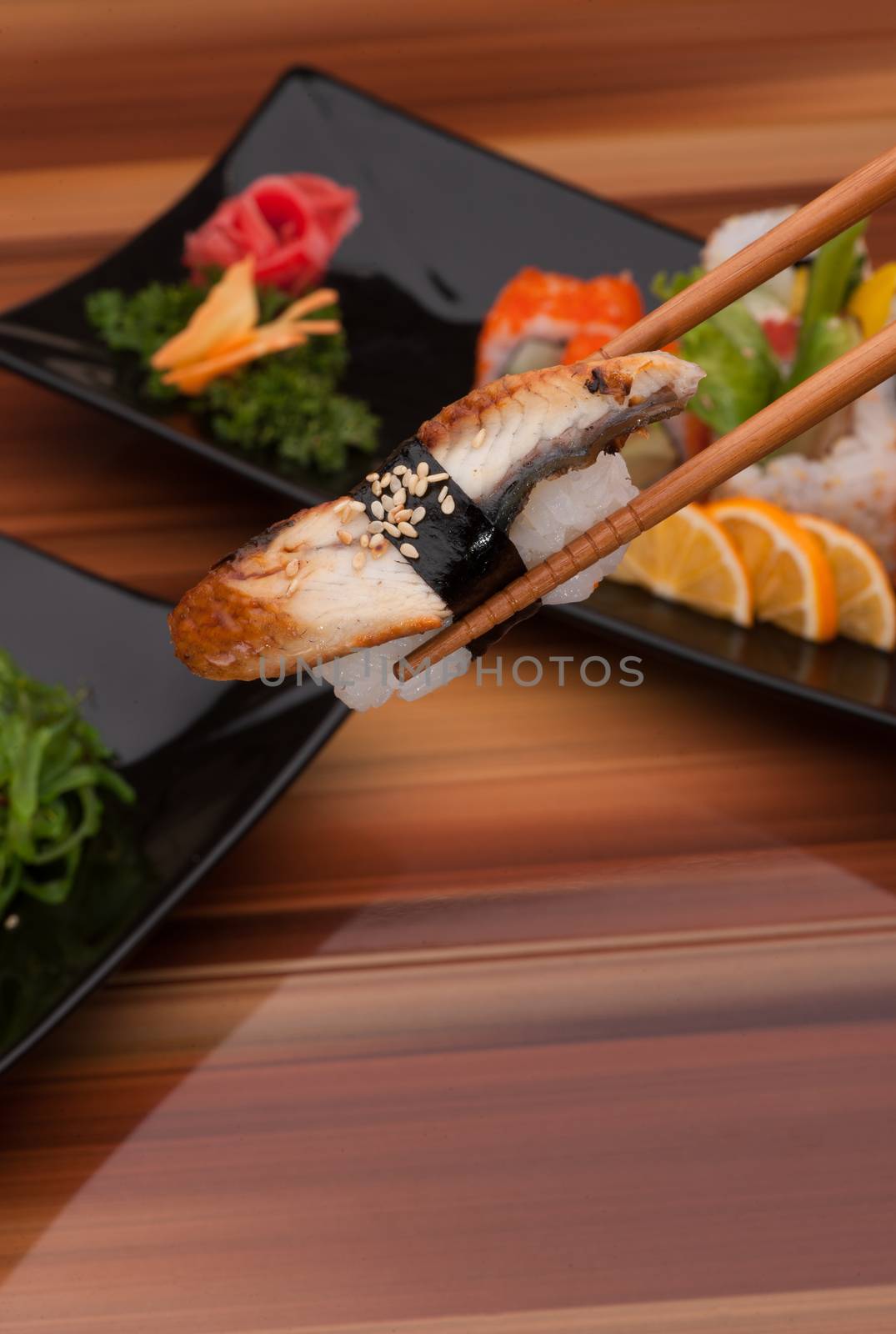 sushi on chopsticks close up on a background of sushi dishes