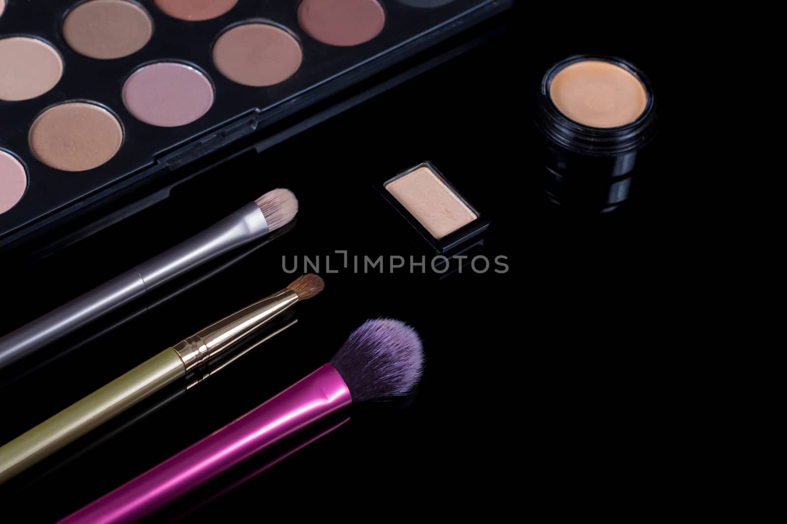 Makeup brushes on black background. Cosmetics, fashion, beauty, glamour. Accessories for make-up artist. Eyeshadow palette, concealer, powder, blush