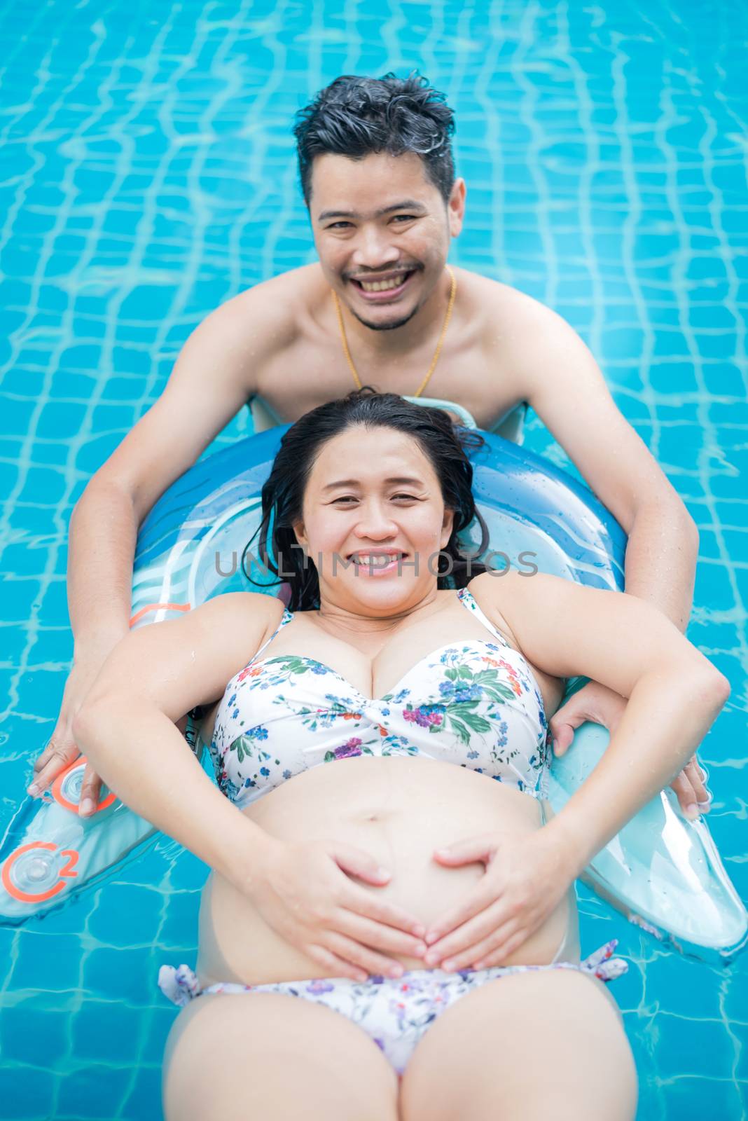 Asian pregnant woman. Mom and newborn baby. Mother day and International women day. Relax and recreation with husband at swimming pool.