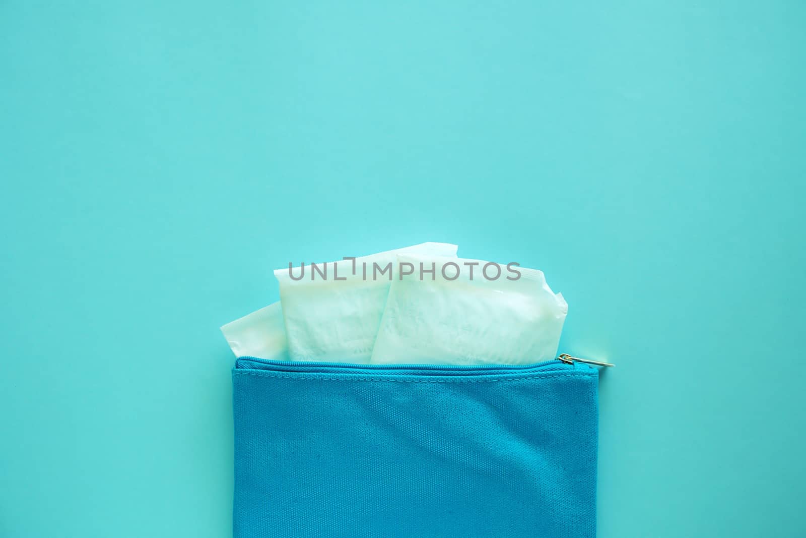 Sanitary napkin in women's fabric bag on blue background for hygiene and health concept