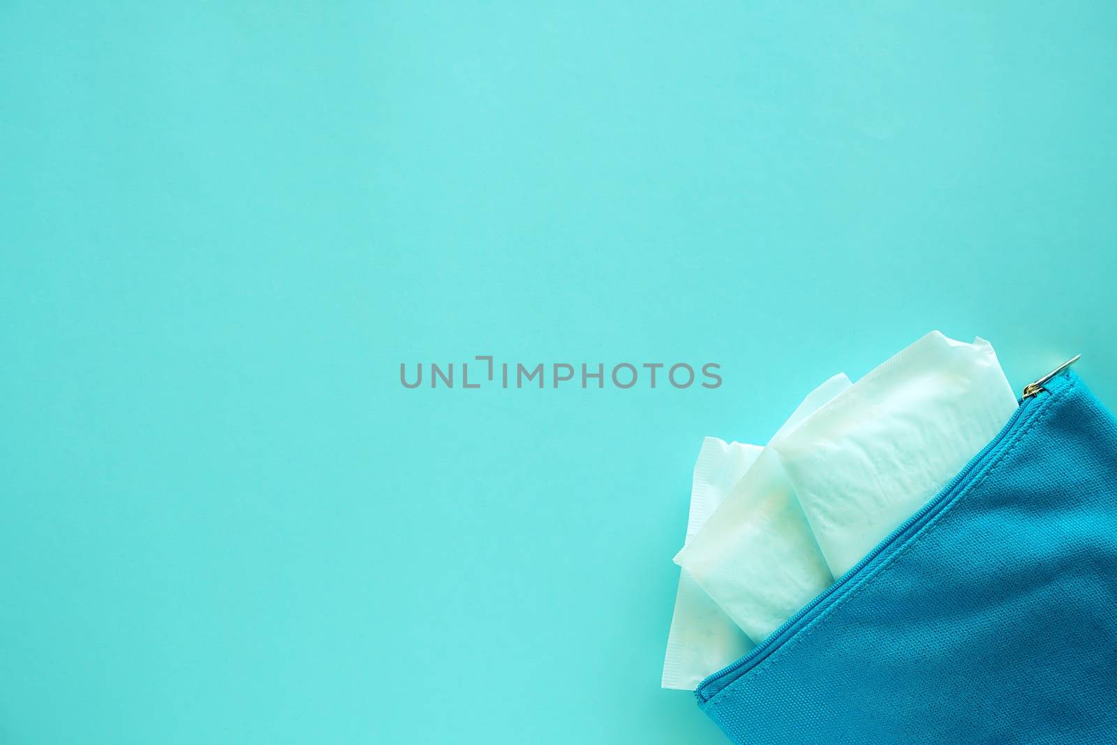 Sanitary napkin in women's fabric bag on blue background for hygiene and health concept