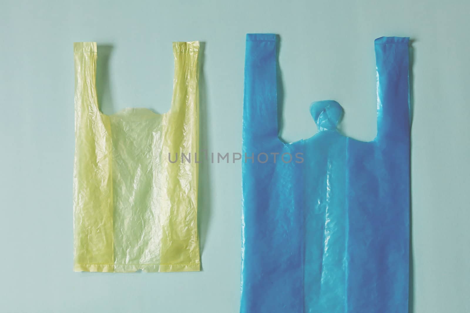 Empty plastic bag against light blue background for waste recycling concept