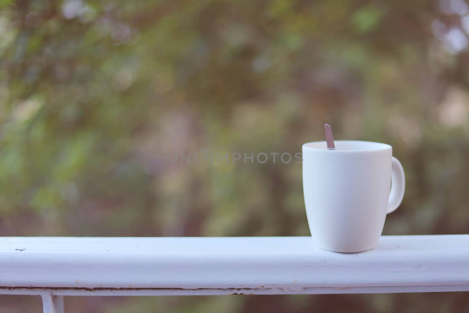 White coffee cup against blurred natural green background for drinks and beverage concept
