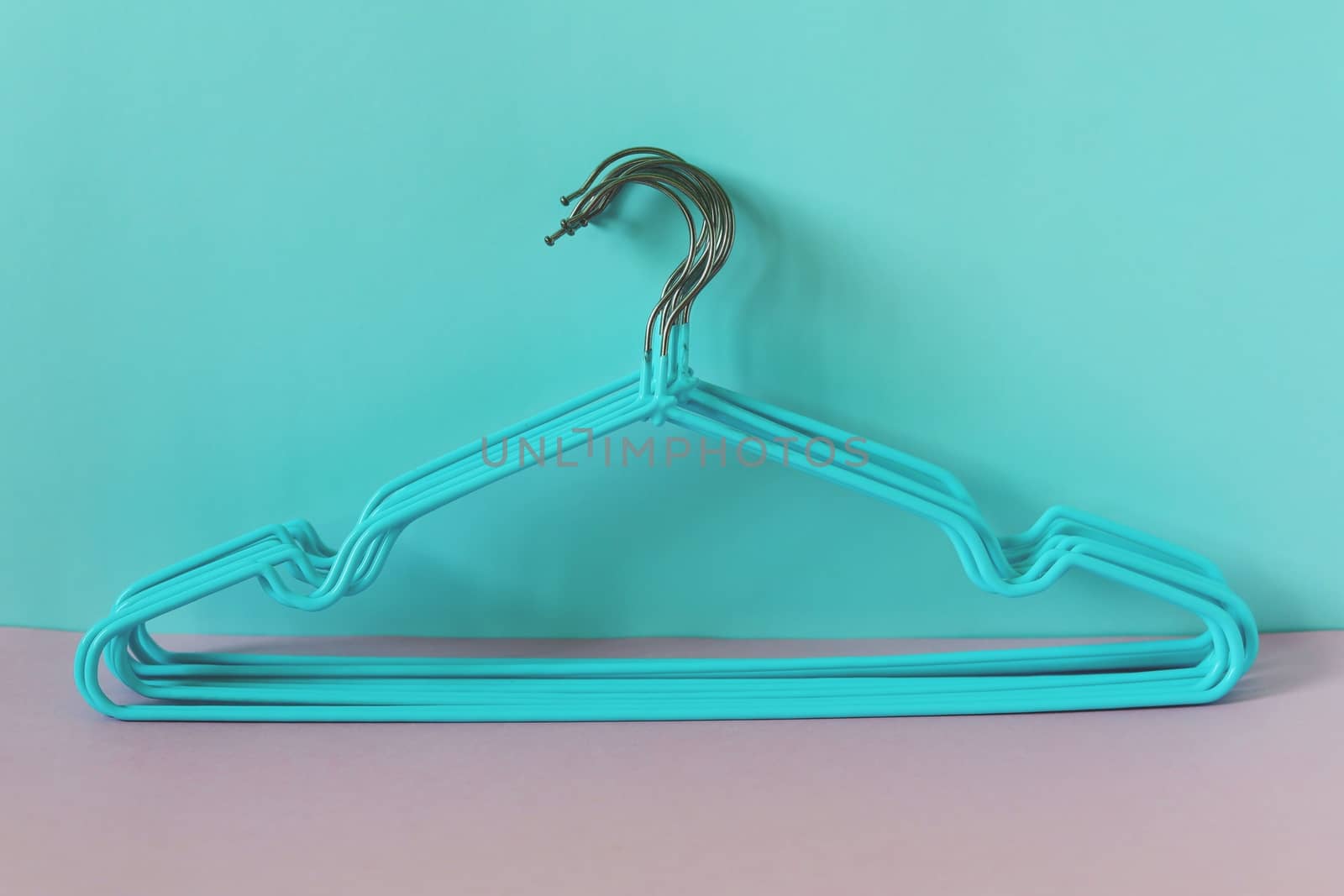 Clothes hangers on blue-pink background for household items.
