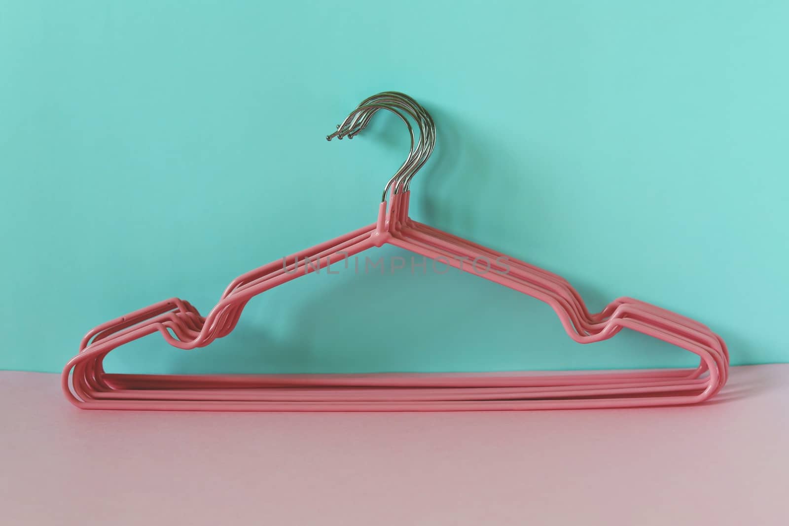 Clothes hangers on blue-pink background for household items.