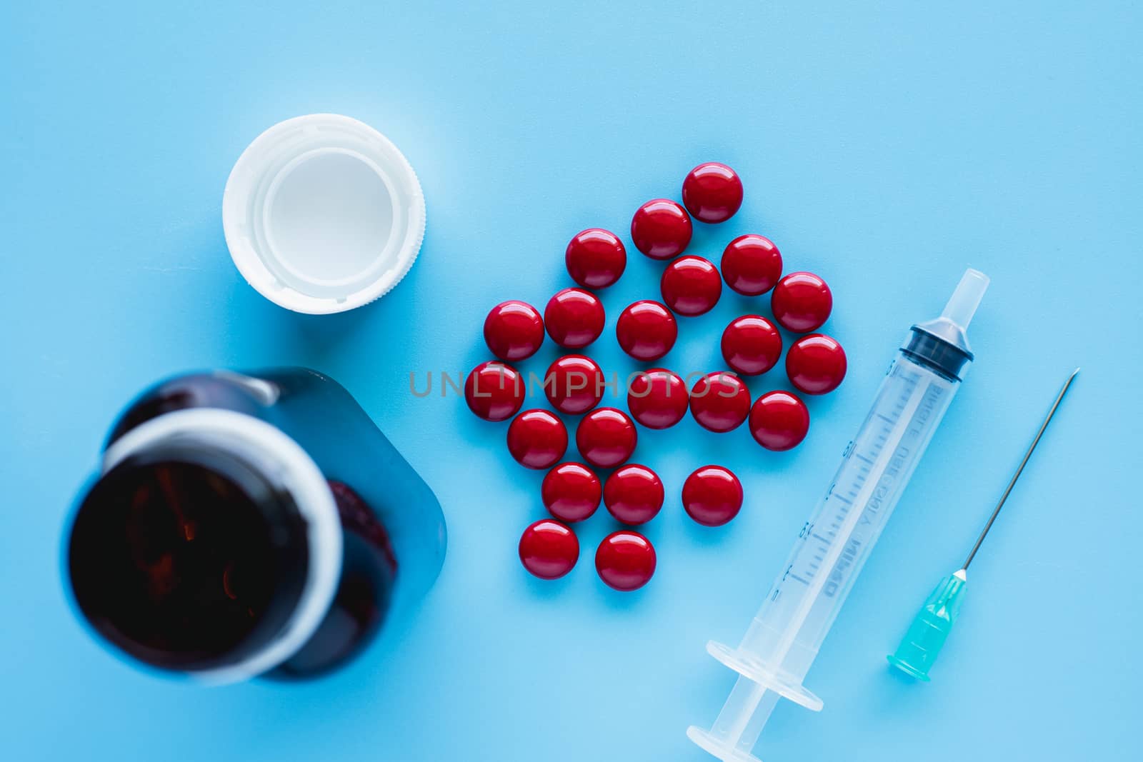 Blood tonic includes multivitamins, folic acid, and iron liquid with bottle and syringe injection on blue background for healthcare and medical concept