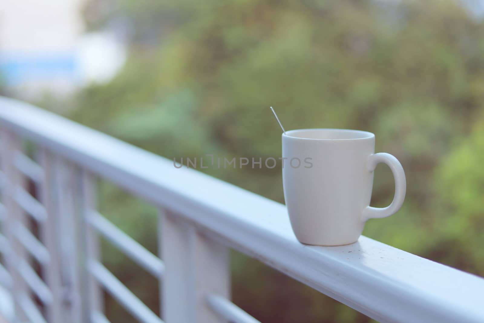 White coffee cup against blurred natural green background for drinks and beverage concept