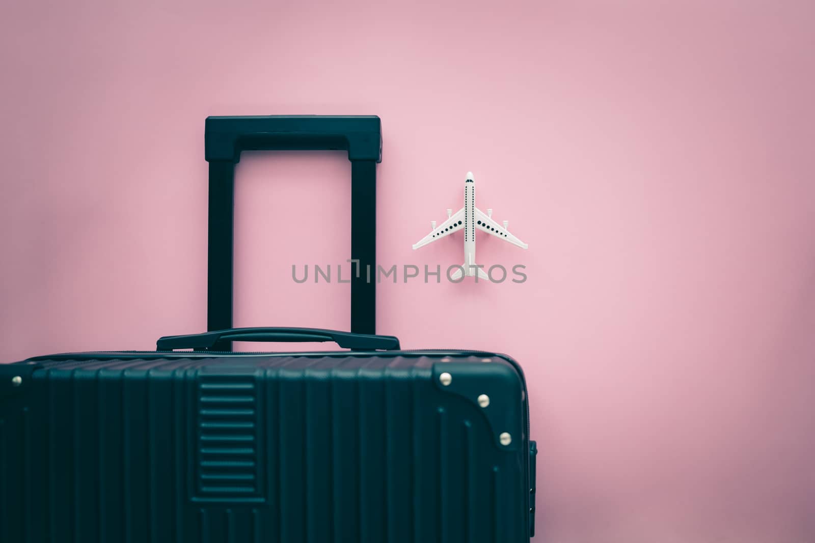 Black luggage and white airplane model on pink background by iamnoonmai