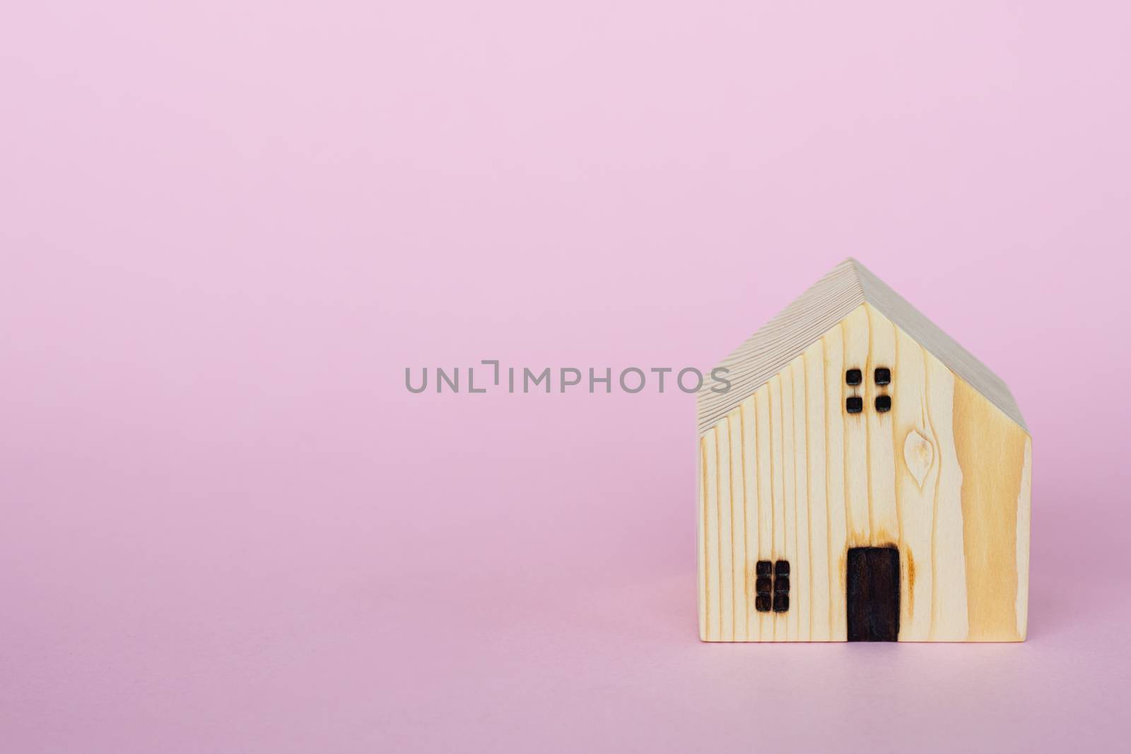 Wooden house model on pink background with copy space for housing concept
