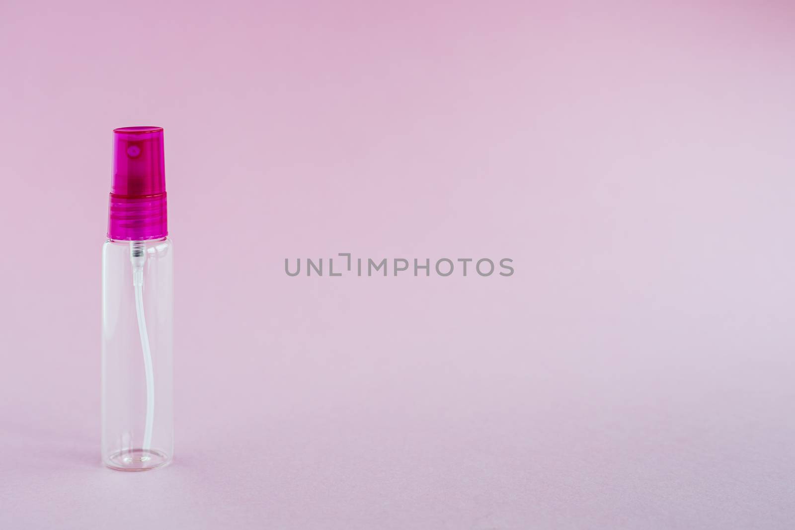 Transparent glass perfume and cosmetic spray bottle on pink background for product packaging concept