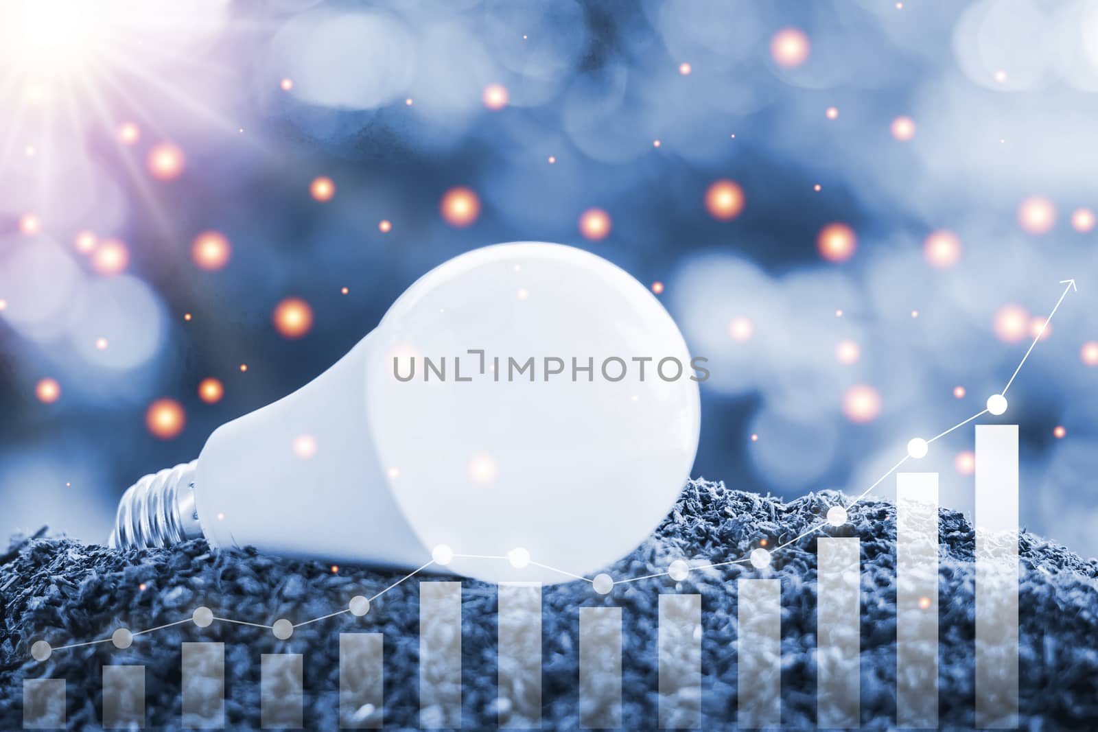 LED light bulb on soil against blurred natural background with growing graph and light effect for electric energy consumption concept