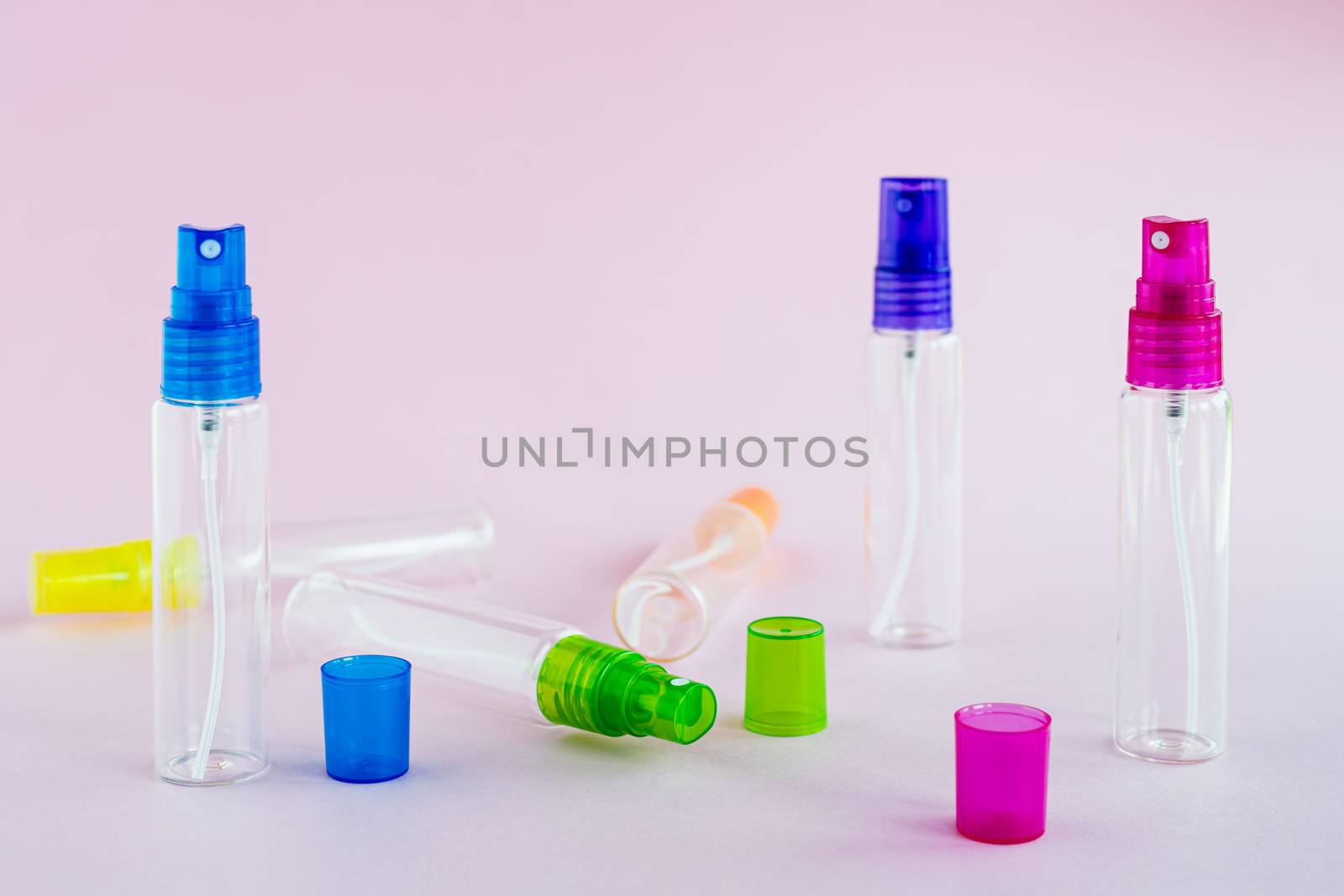 Transparent glass perfume and cosmetic spray bottle on pink background for product packaging concept
