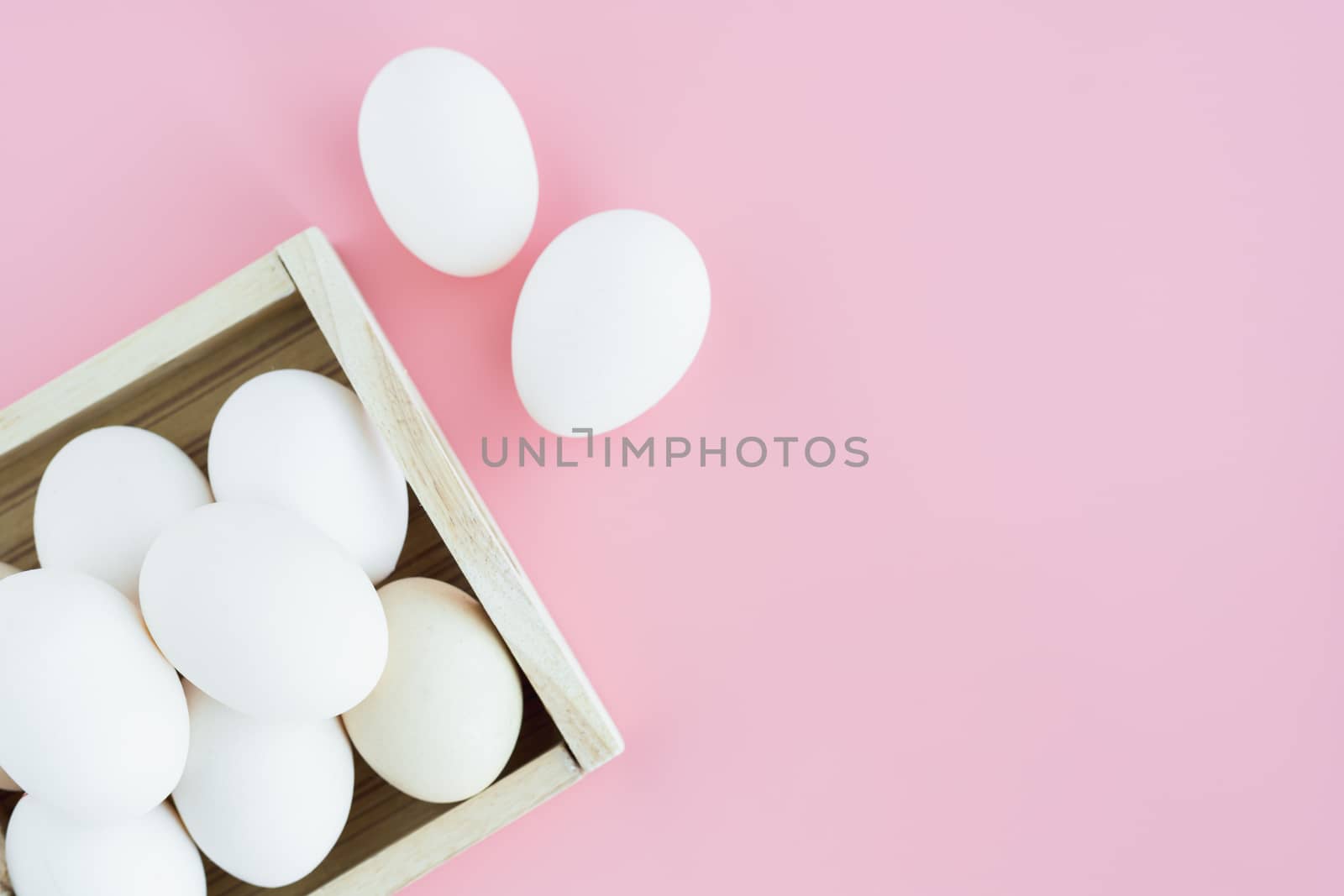 White eggs in the wooden tray on pink background for healthy food concept