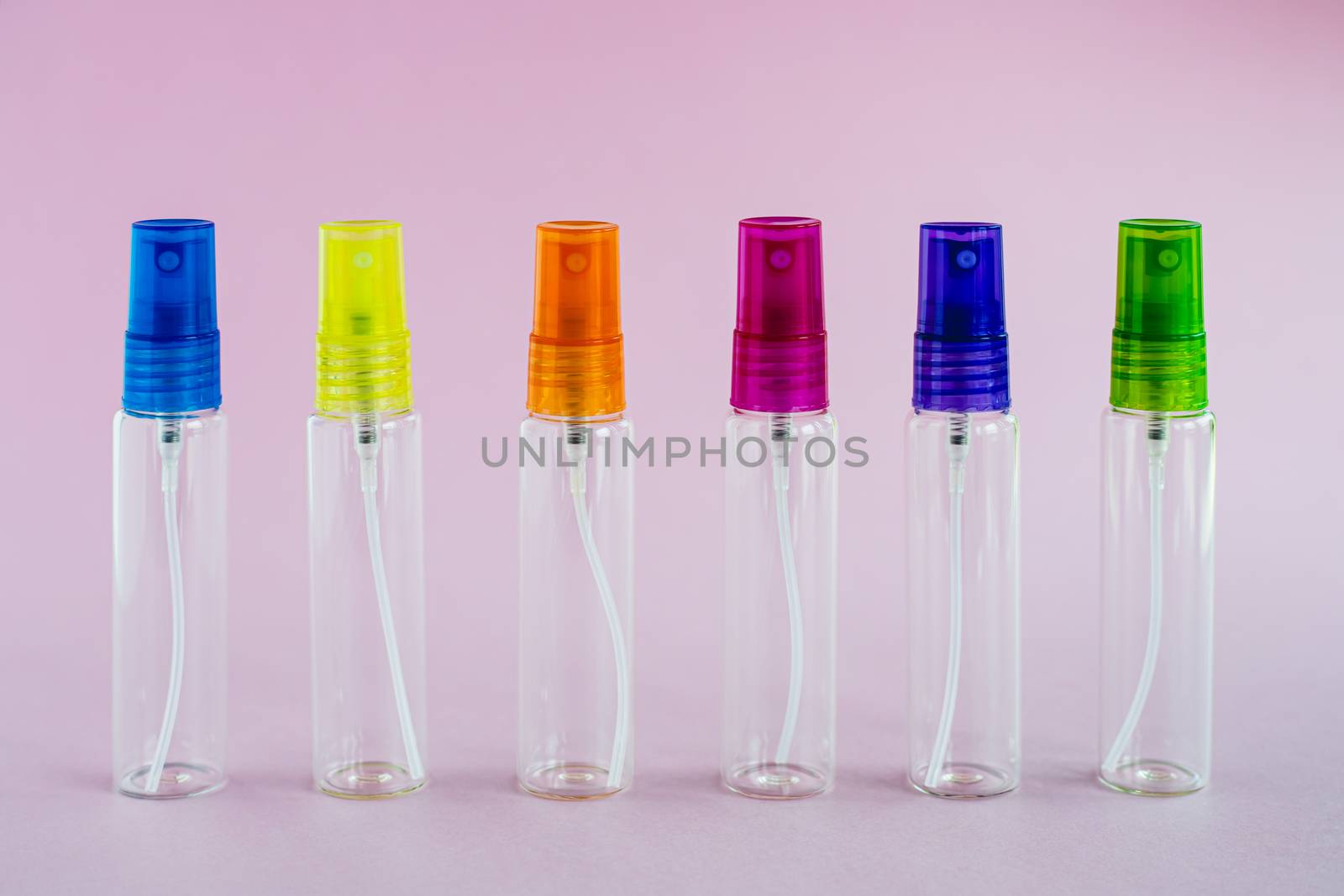 Transparent glass perfume and cosmetic spray bottle on pink background for product packaging concept