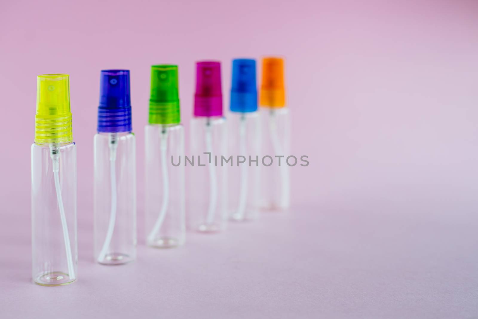 Transparent glass perfume and cosmetic spray bottle on pink background for product packaging concept
