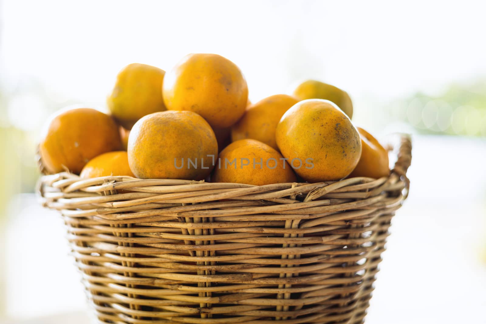 Orange in the wicker basket against blurred outdoor background for fruit and eating concept