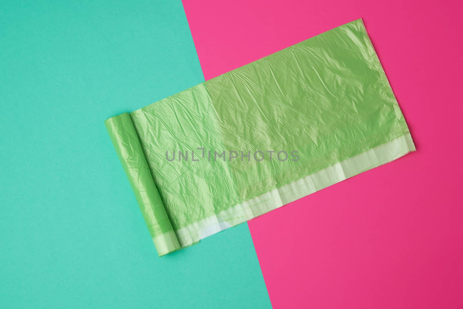 green transparent plastic bag for garbage on a colored background, top view