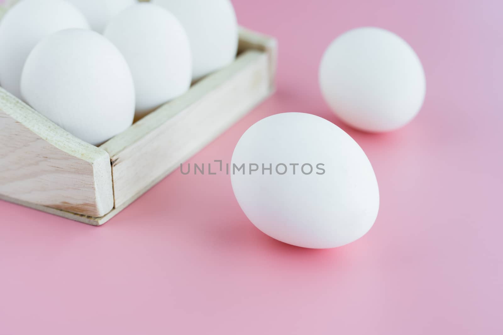 White eggs in the wooden tray on pink background for healthy food concept
