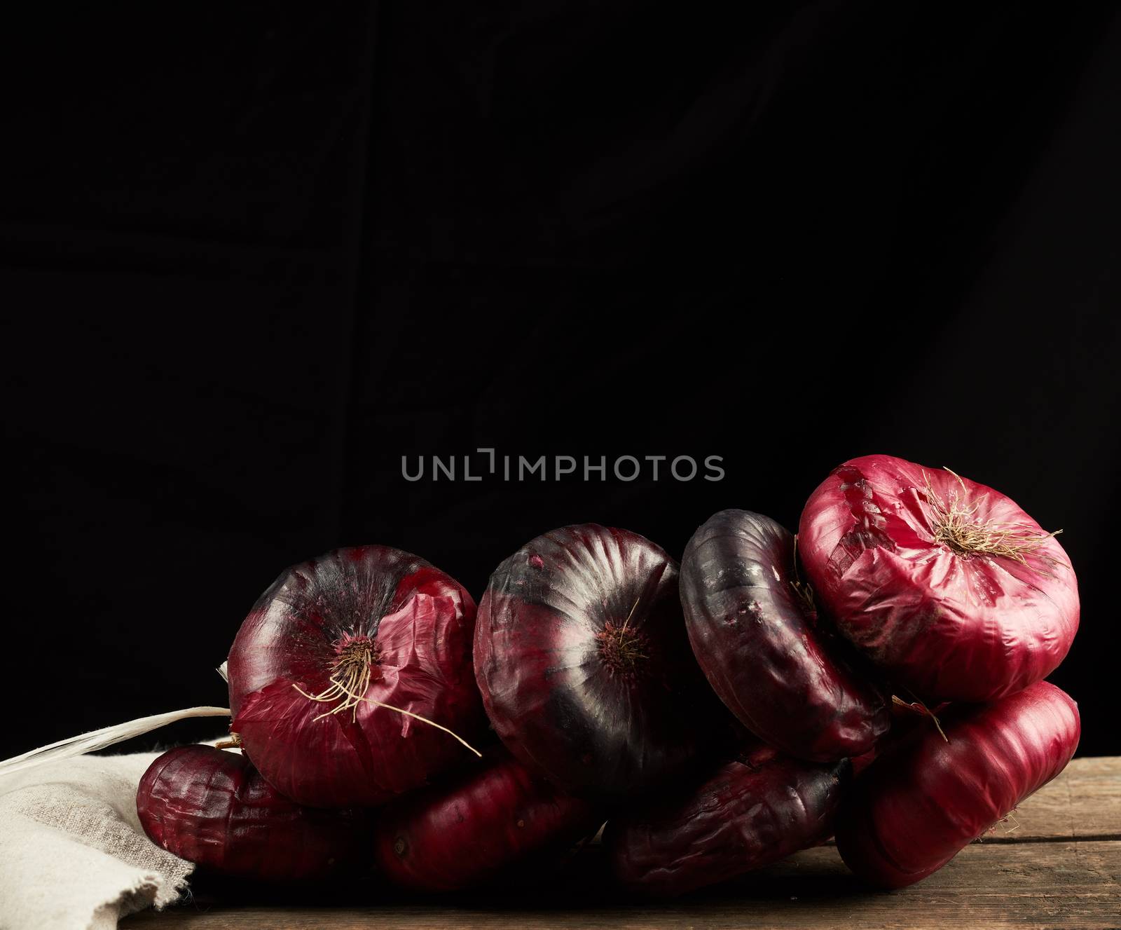 round red onion in husk on a gray linen napkin, black background, close up