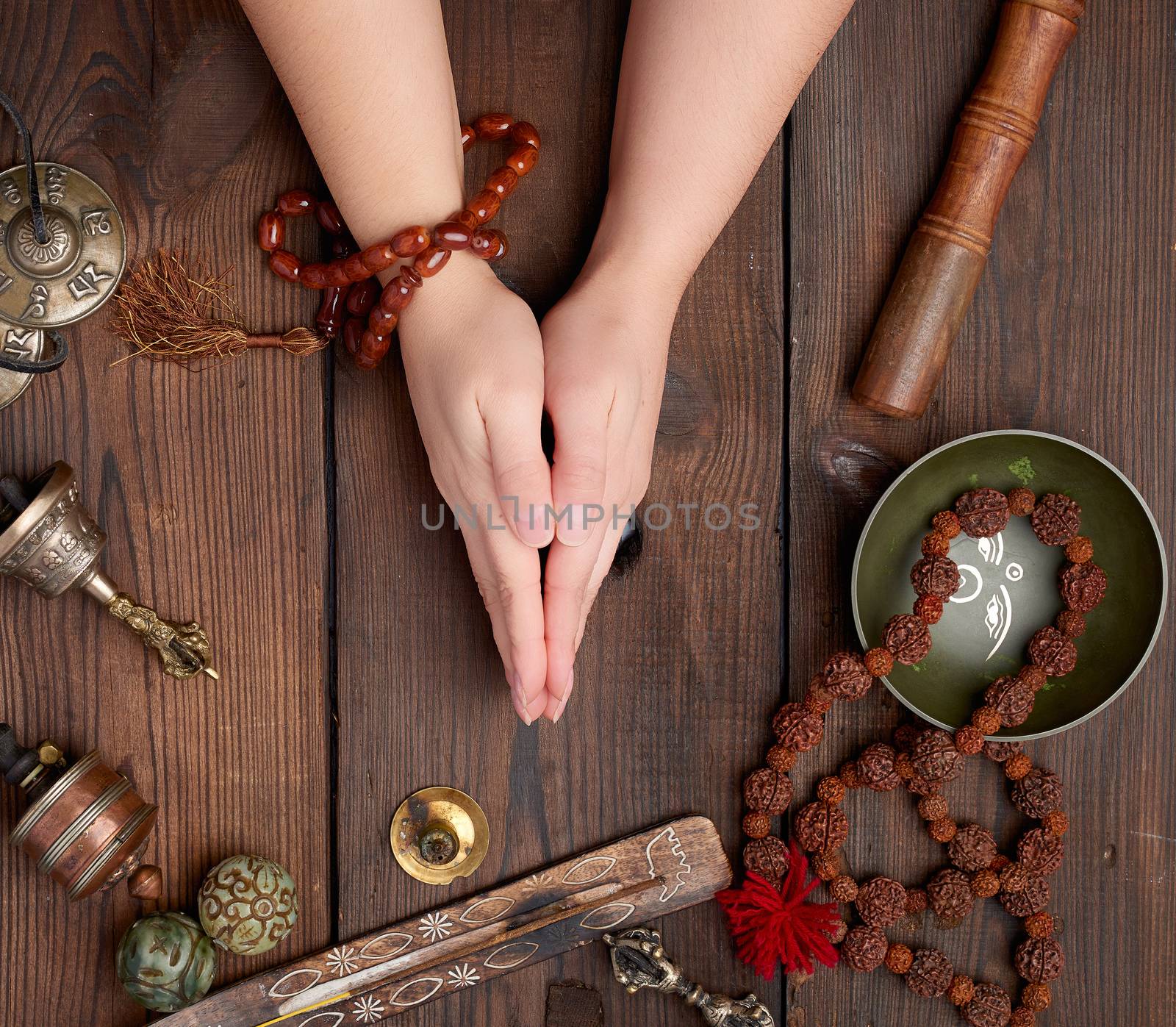 two hands in a prayer pose on a wooden brown table in the middle by ndanko