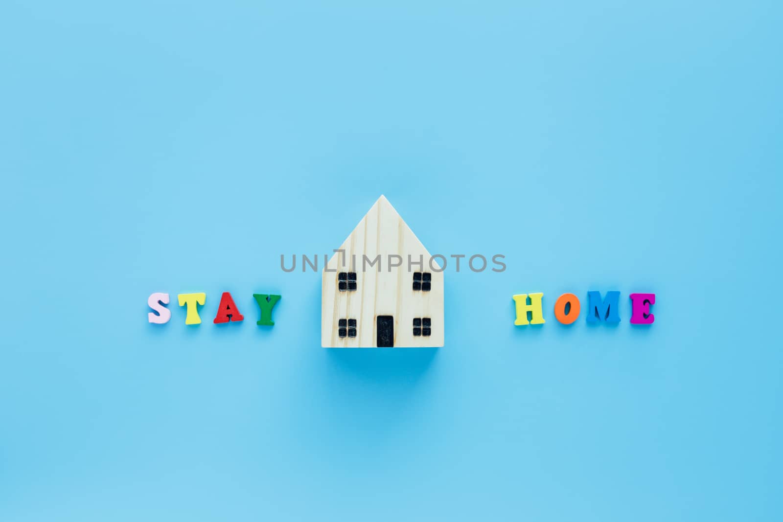 Stay home text with wooden house model on blue background for self-quarantine, staying home and social distancing in coronavirus or Covid-2019 situation concept
