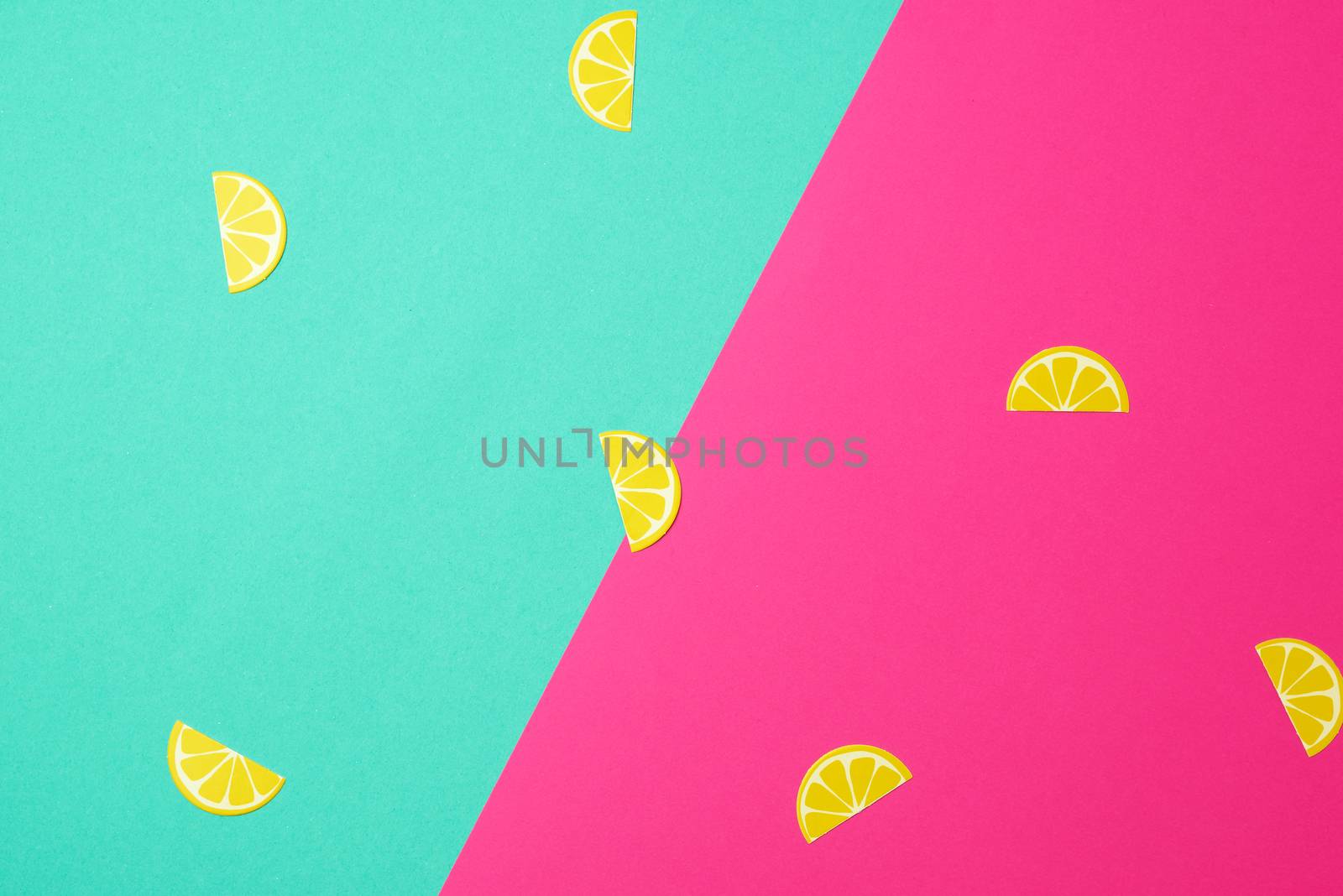 abstract green-pink background with paper yellow lemon slices, close up
