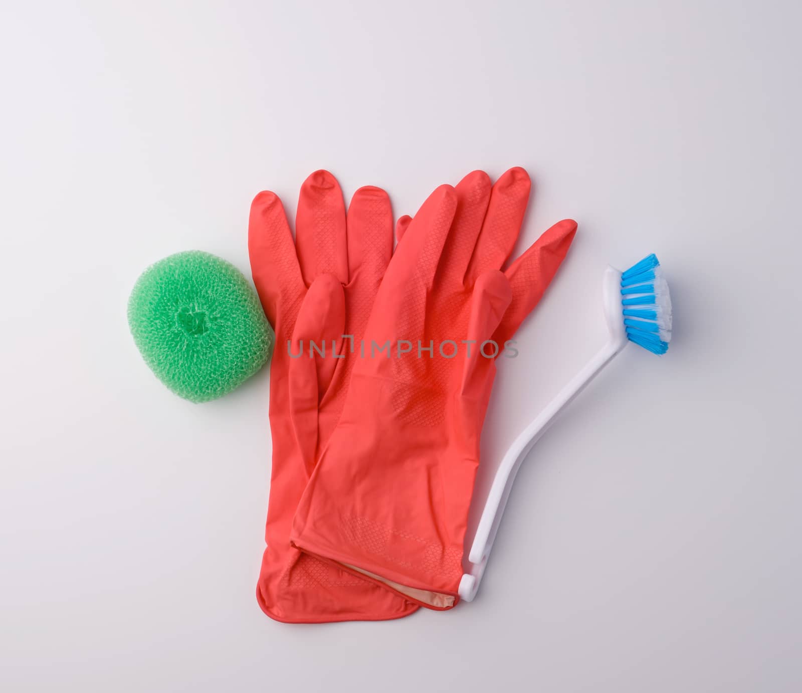 items for home cleaning: red rubber gloves, brush, multi-colored sponges for dusting on a white background, top view, flat lay