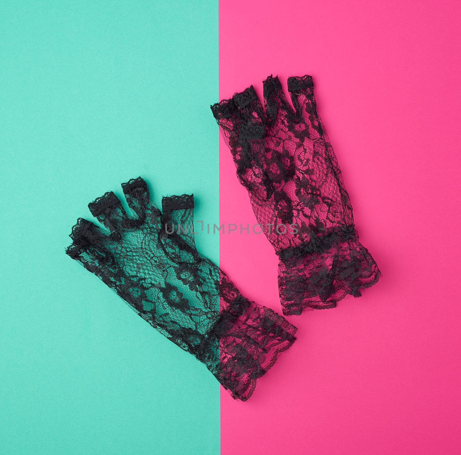 black lace gloves on a pink-green background, top view