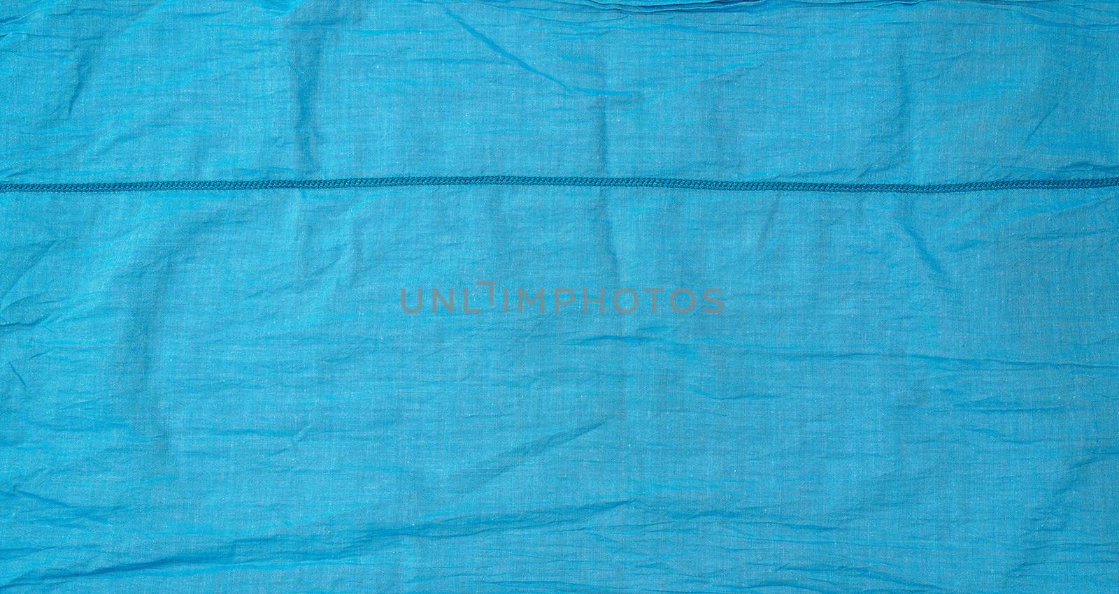 fragment of blue cotton fabric with a seam, full frame, close up