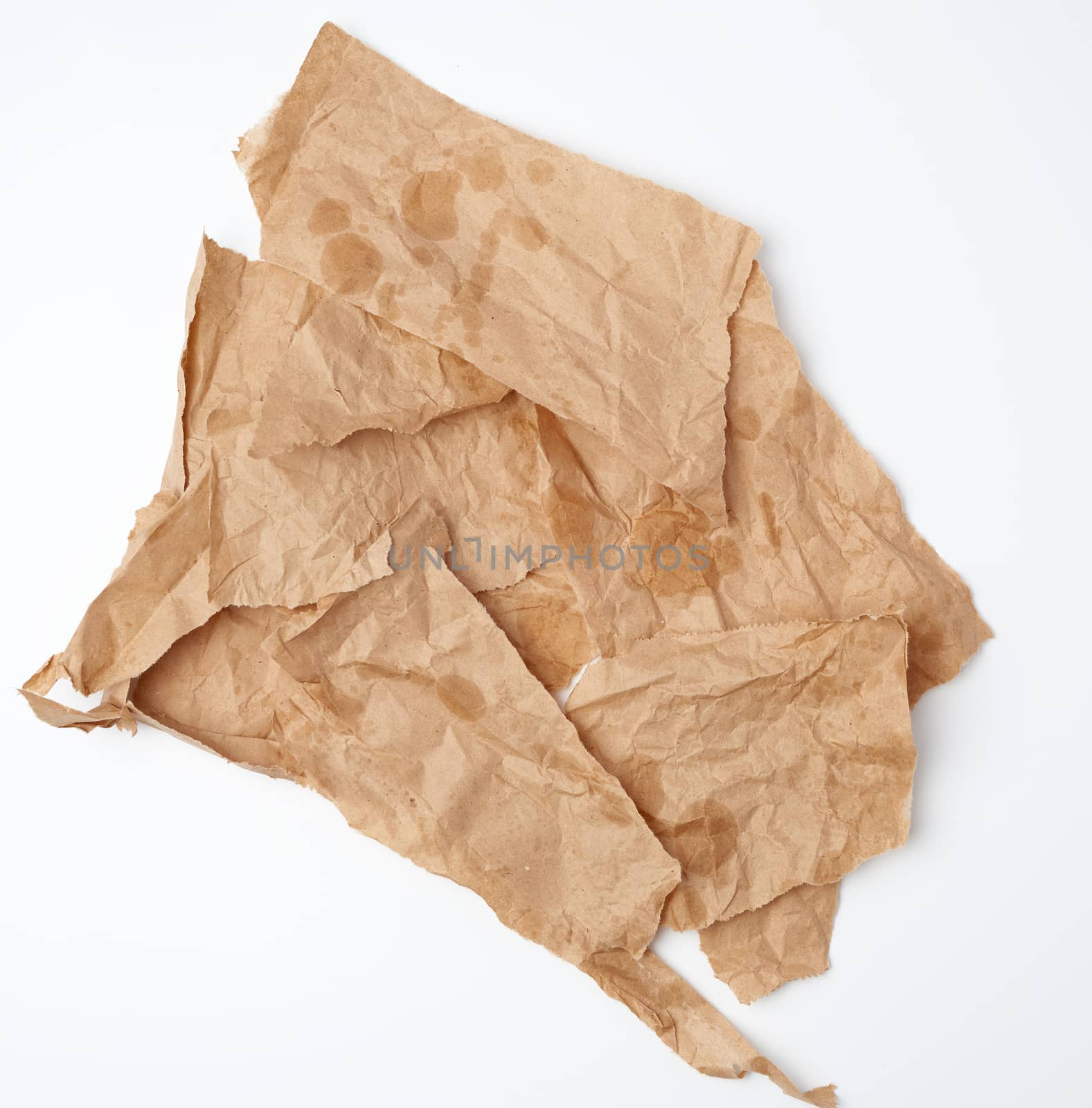 torn crumpled pieces of brown paper with grease stains on a white background, top view