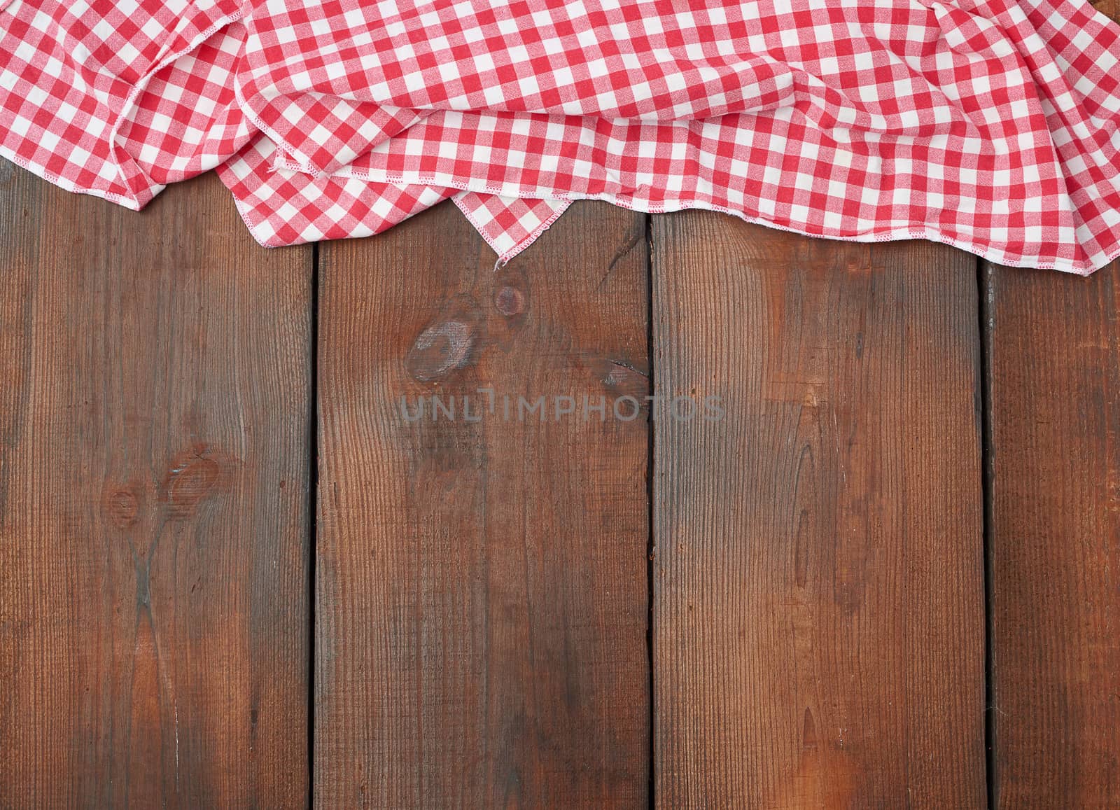 white red checkered kitchen towel on a brown wooden background, picnic background, copy space