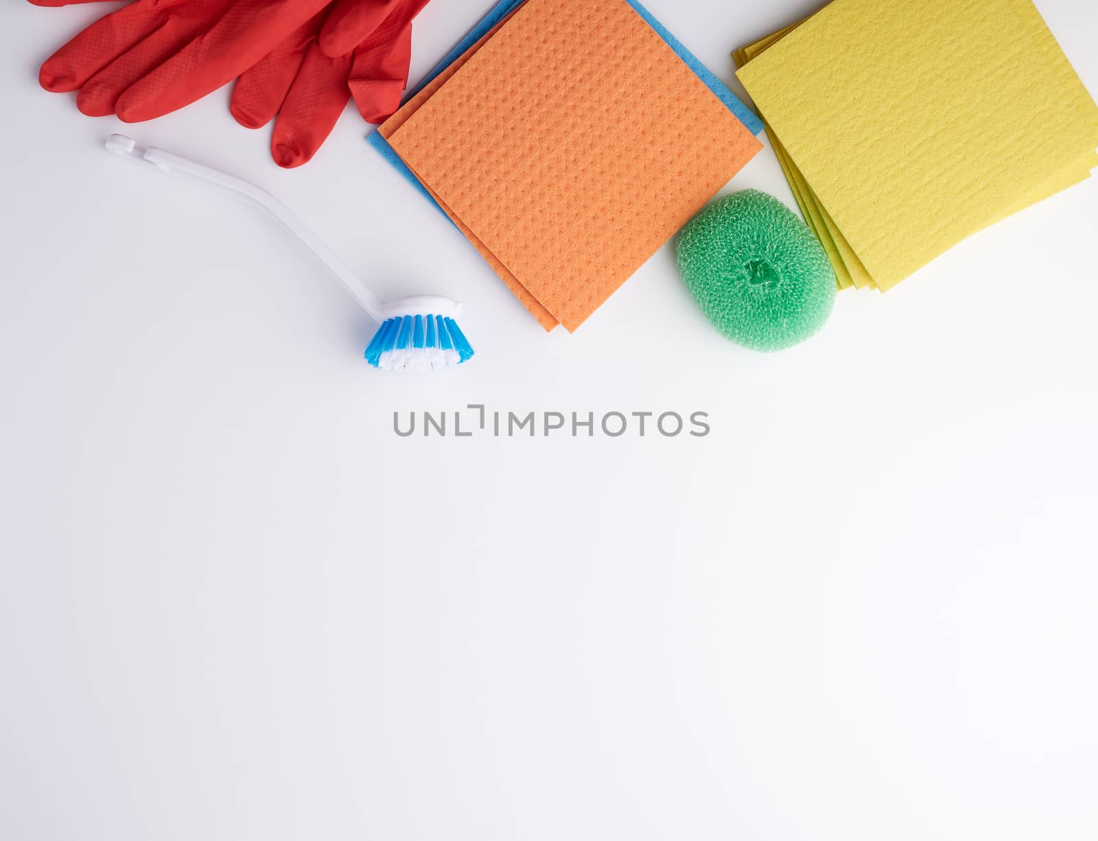 items for home cleaning: red rubber gloves, brush, multi-colored sponges for dusting on a white background, top view, flat lay