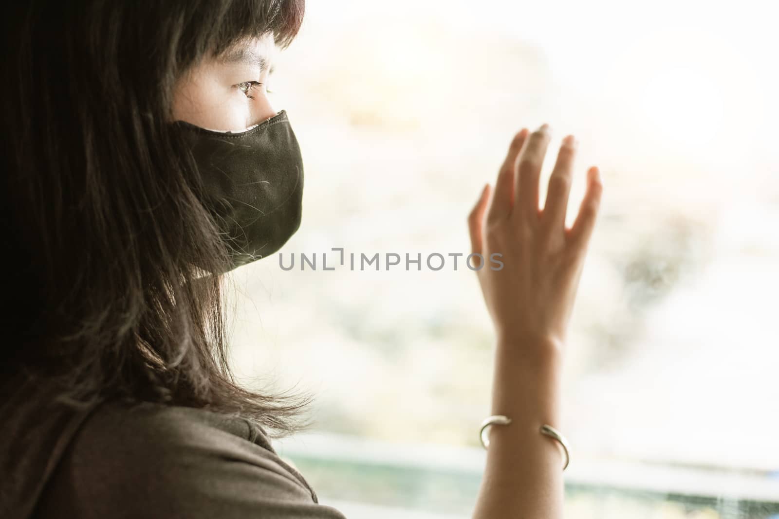 Asian woman wearing a black face mask, standing absent-minded at the door and staying home for self-quarantine and social distancing in coronavirus or Covid-2019 outbreak situation concept