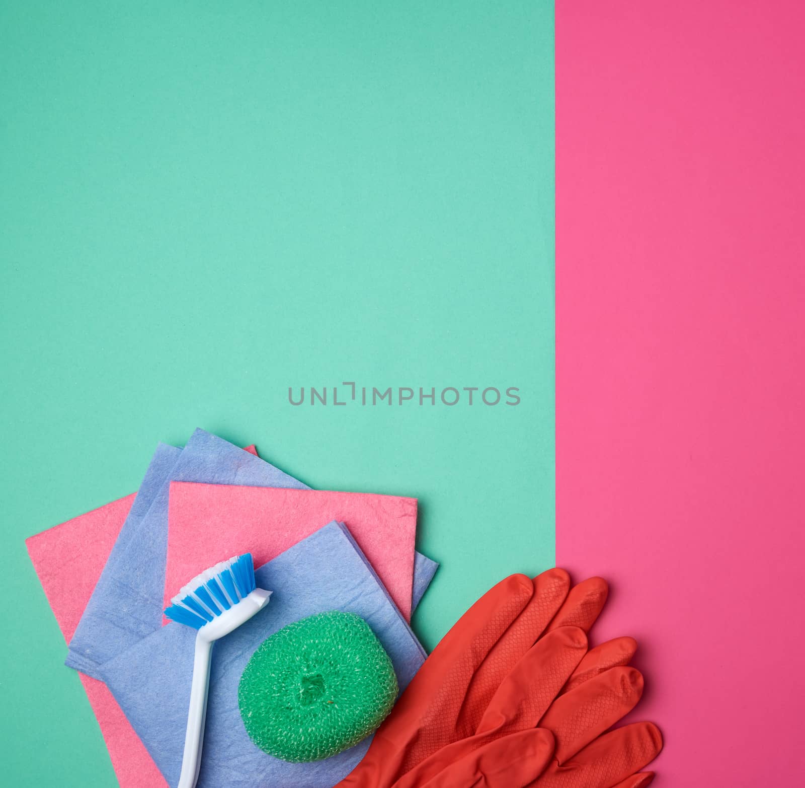 items for home cleaning: red rubber gloves, brush, multi-colored sponges for dusting on a pink green background, top view, flat lay