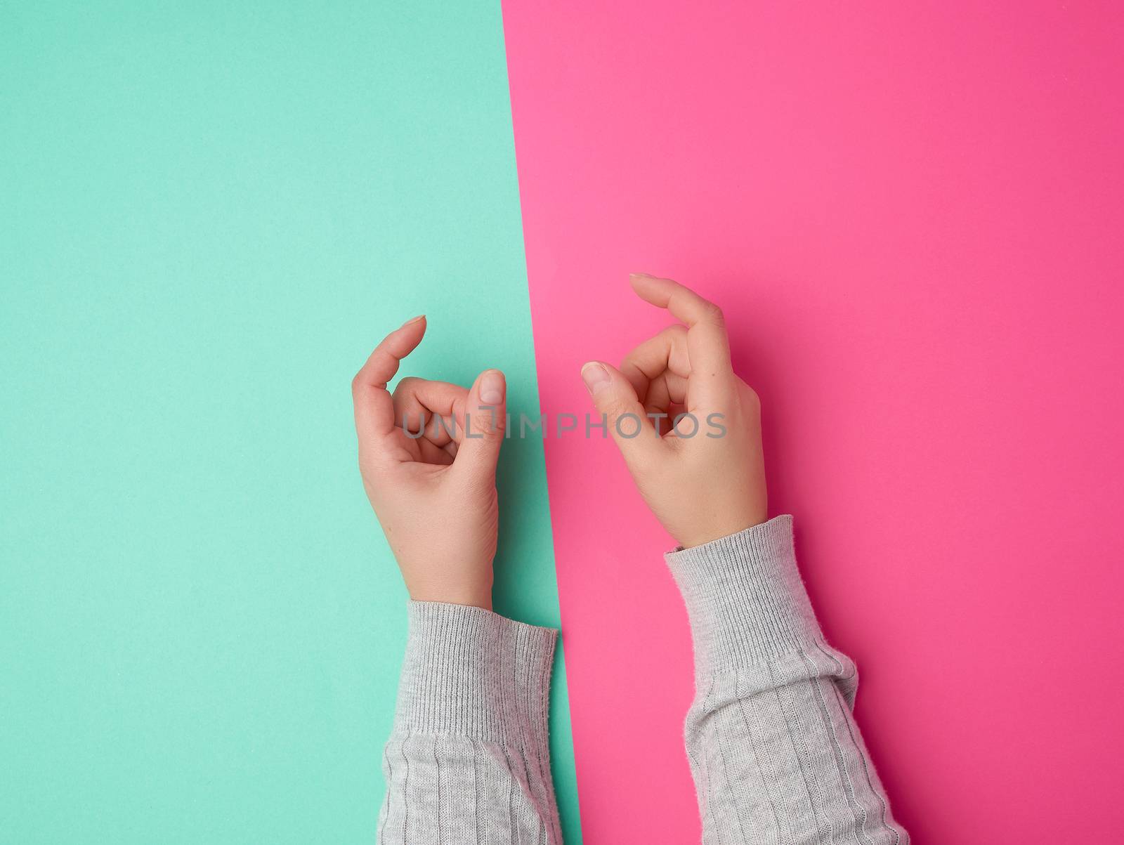 female hands on a green pink background, fingers in the gesture of holding the subject, copy space