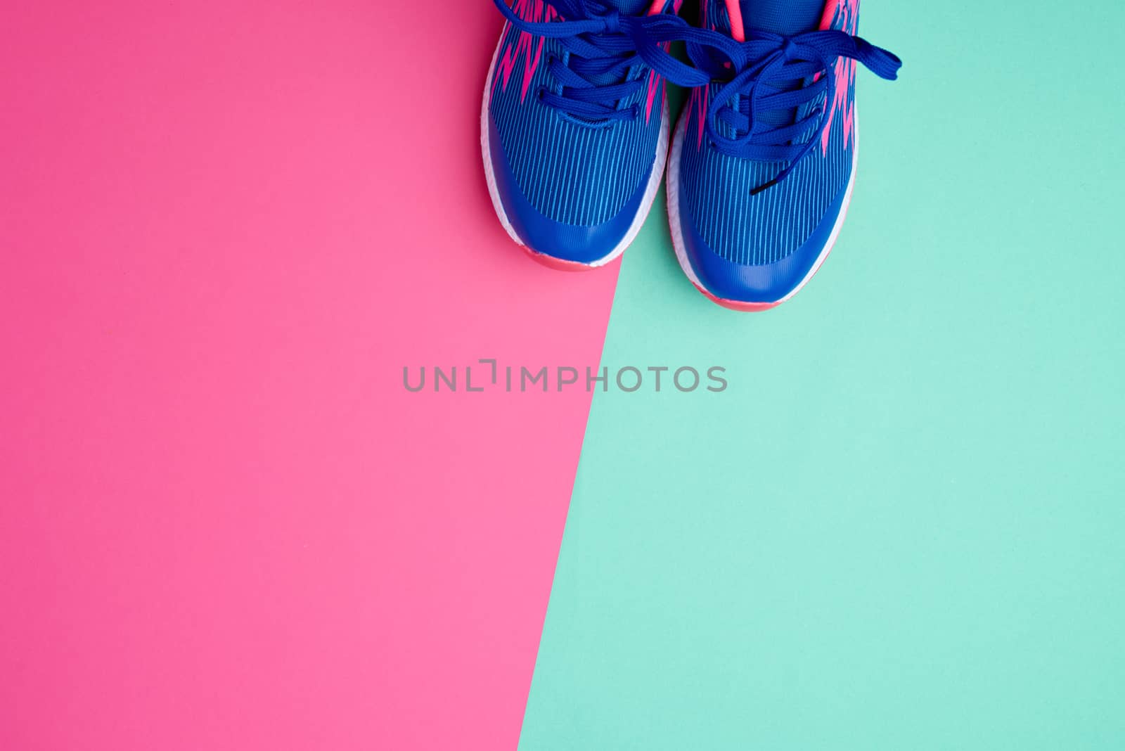 pair of sports sneakers with blue laces on a colored abstract background, copy space	