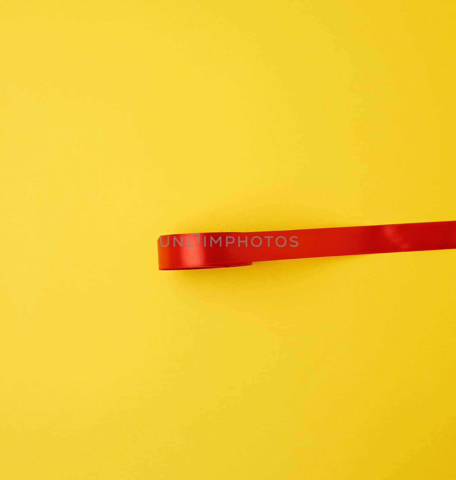 red silk ribbon on a yellow background, festive backdrop, place for text