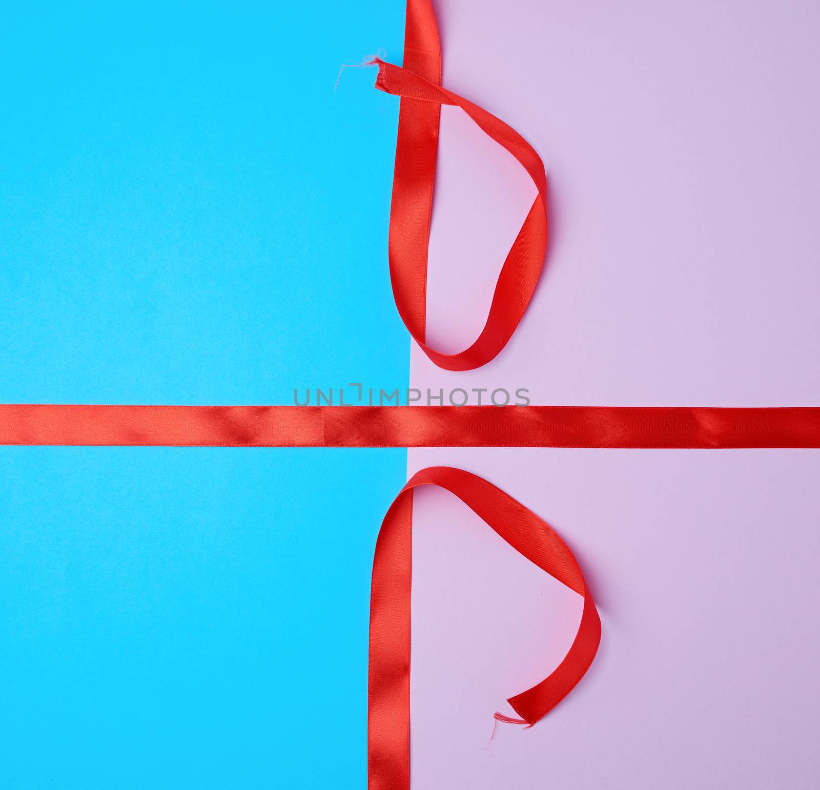 red satin ribbon on a colored background, imitation of tying and packing a gift