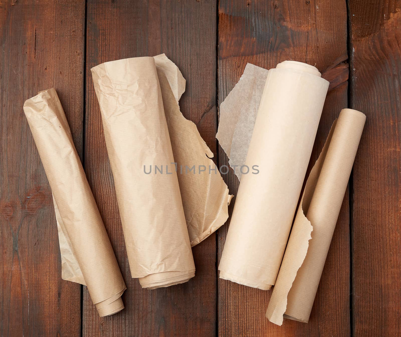 four rolled rolls of brown parchment paper on a wooden background, top view