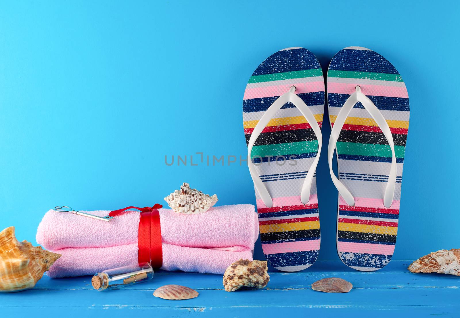 pair of female beach slippers and a towels on a blue background, concept of a vacation at sea